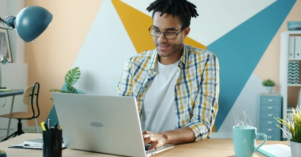 Jeune homme dans un bureau élégant utilisant un ordinateur portable, incarnant un environnement de travail moderne.