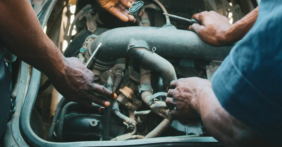Des mécaniciens travaillant sur un moteur de voiture à AK, Nigeria, mettant en valeur le travail d'équipe.