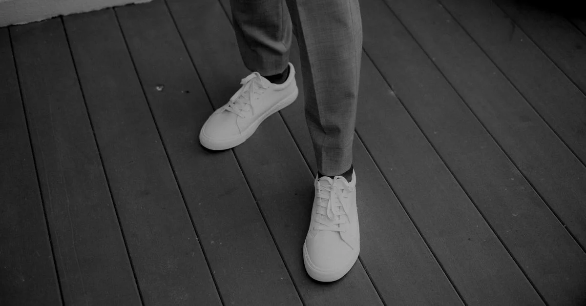 Gros plan en noir et blanc de baskets blanches modernes sur une terrasse en bois.