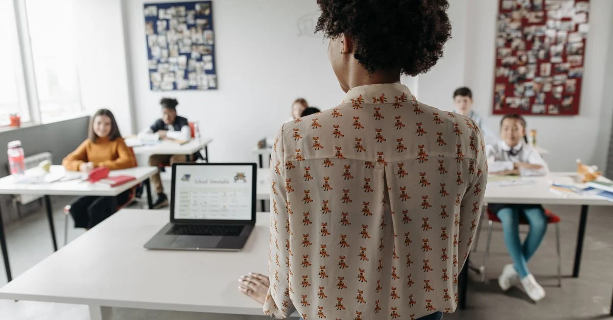 Enseignante engageant des élèves dans une salle de classe avec des apprenants divers.